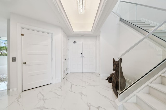 interior space with baseboards, a raised ceiling, marble finish floor, and stairway