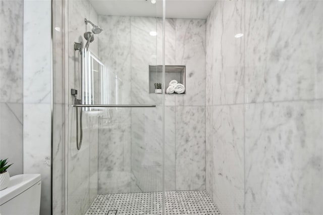 bathroom with a marble finish shower and toilet
