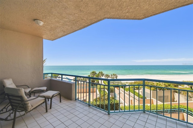 balcony with a water view and a view of the beach