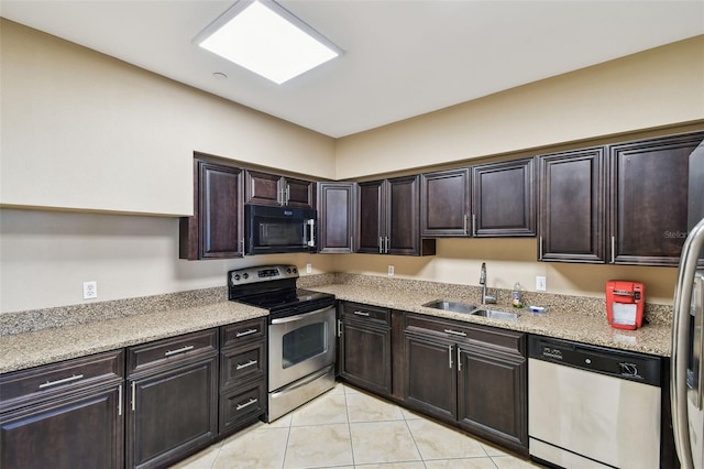 kitchen featuring stainless steel appliances, light tile patterned flooring, a sink, and dark brown cabinets