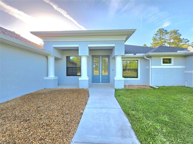 11240 Marvelwood, Brooksville, FL 34614 - property entrance featuring roof with shingles, stucco siding, and a lawn