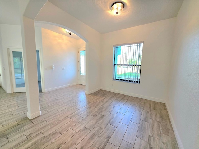 11240 Marvelwood, Brooksville, FL 34614 - spare room with baseboards, light wood-style flooring, and arched walkways