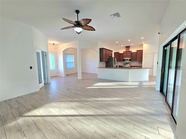 11240 Marvelwood, Brooksville, FL 34614 - unfurnished living room featuring a ceiling fan, baseboards, visible vents, wood finish floors, and arched walkways