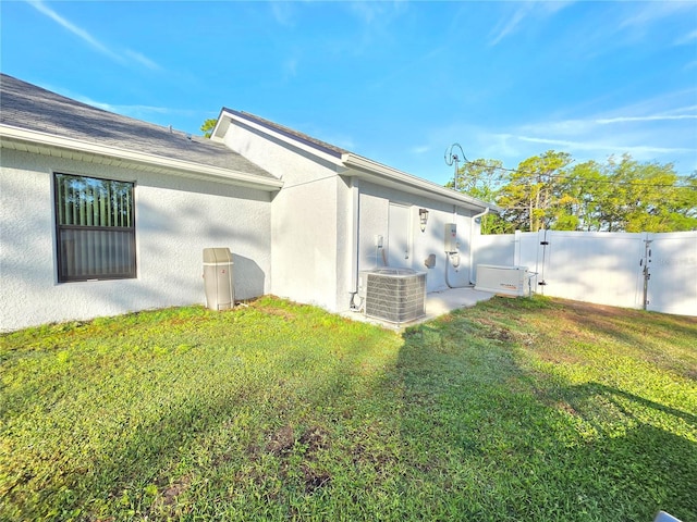 11240 Marvelwood, Brooksville, FL 34614 - view of side of property with central air condition unit, stucco siding, a gate, and a lawn