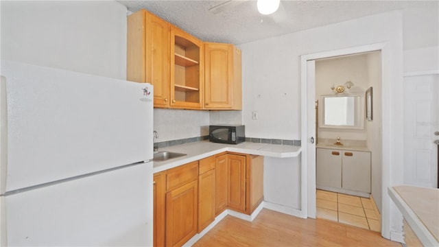 6325 9th Ave S, Gulfport, FL 33707 - kitchen featuring freestanding refrigerator, black microwave, a sink, light countertops, and light wood finished floors