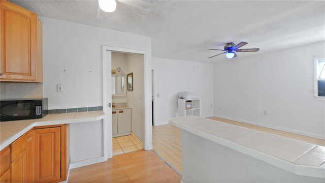 6325 9th Ave S, Gulfport, FL 33707 - kitchen featuring ceiling fan, black microwave, light wood-style flooring, a textured ceiling, and light countertops