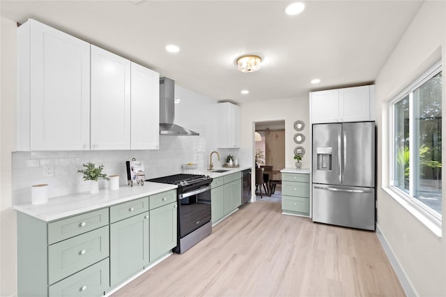 1443 Paloma Ln, Dunedin, FL 34698 - kitchen with stainless steel appliances, wall chimney range hood, a sink, light wood-style floors, and backsplash