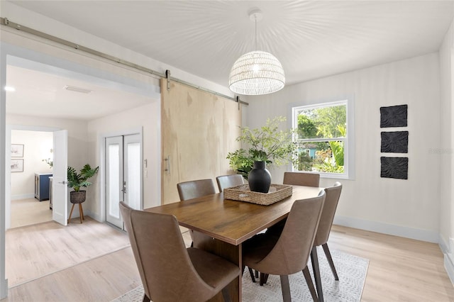 1443 Paloma Ln, Dunedin, FL 34698 - dining space featuring light wood finished floors, a barn door, plenty of natural light, and baseboards