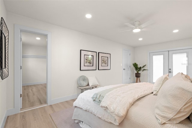 1443 Paloma Ln, Dunedin, FL 34698 - bedroom featuring french doors, light wood finished floors, a walk in closet, recessed lighting, and a ceiling fan