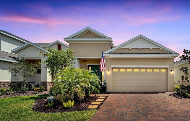 view of front of house featuring an attached garage, stucco siding, and decorative driveway