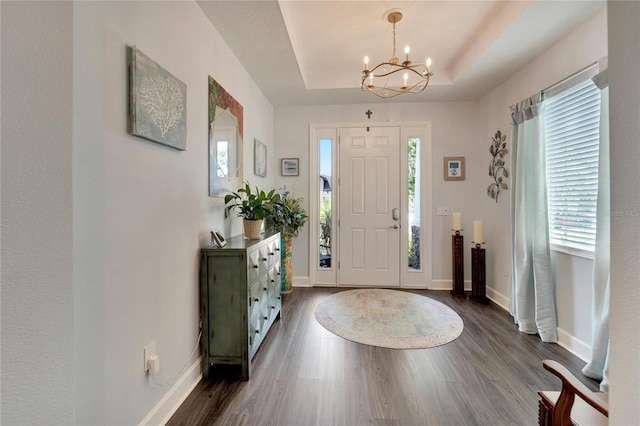 entrance foyer featuring a chandelier, baseboards, dark wood finished floors, and a raised ceiling