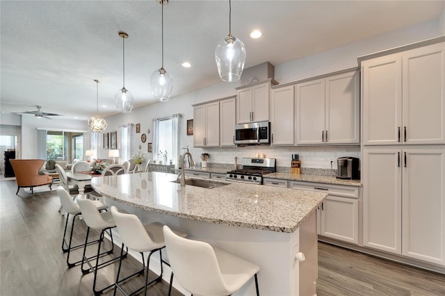 kitchen featuring a sink, appliances with stainless steel finishes, wood finished floors, and a healthy amount of sunlight