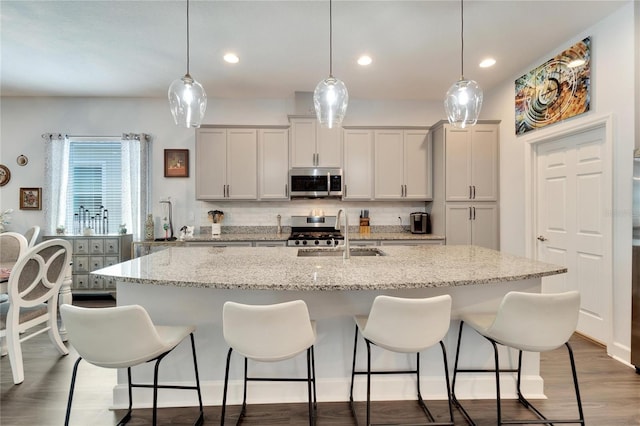 kitchen featuring a sink, appliances with stainless steel finishes, a breakfast bar area, and backsplash