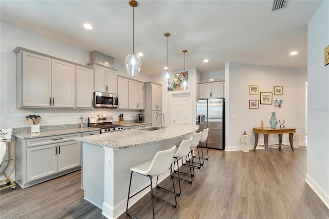 kitchen featuring visible vents, appliances with stainless steel finishes, tasteful backsplash, a sink, and light wood finished floors