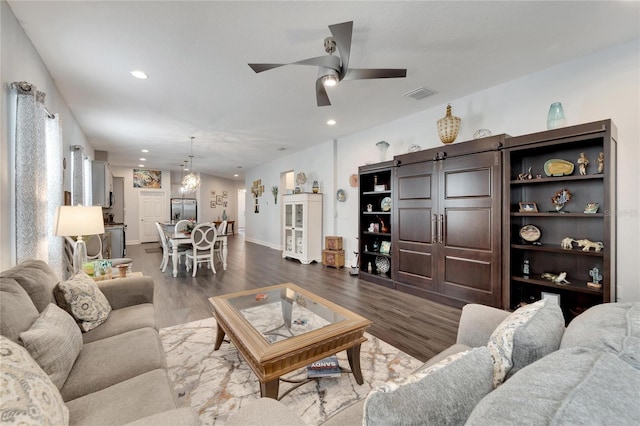 living room featuring a ceiling fan, a barn door, wood finished floors, baseboards, and recessed lighting