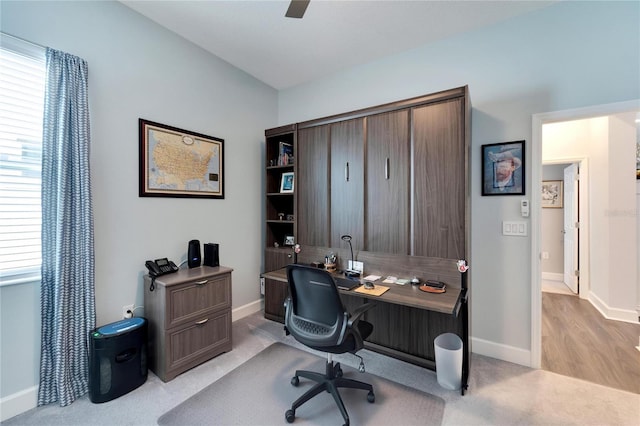 office space featuring baseboards, ceiling fan, and light colored carpet