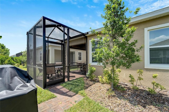 view of property exterior featuring glass enclosure, a patio, and stucco siding