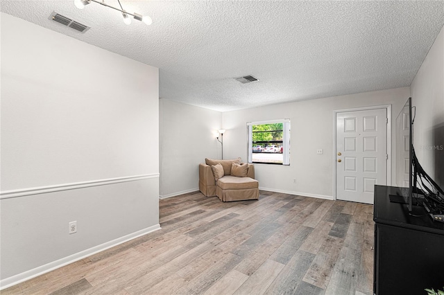 sitting room with visible vents, a textured ceiling, and wood finished floors