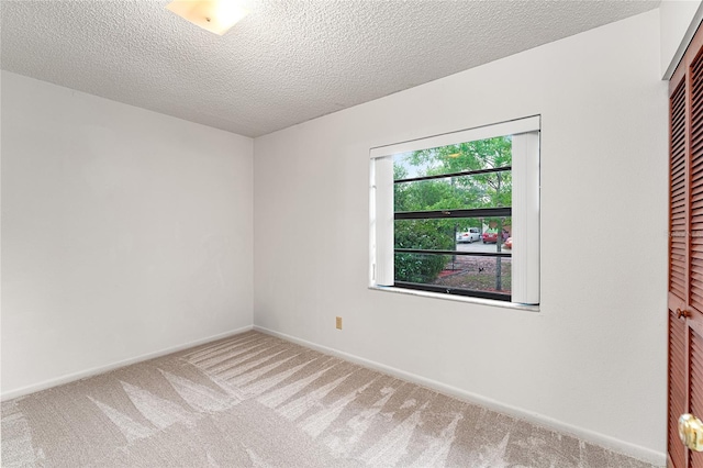 unfurnished room featuring baseboards, carpet flooring, and a textured ceiling
