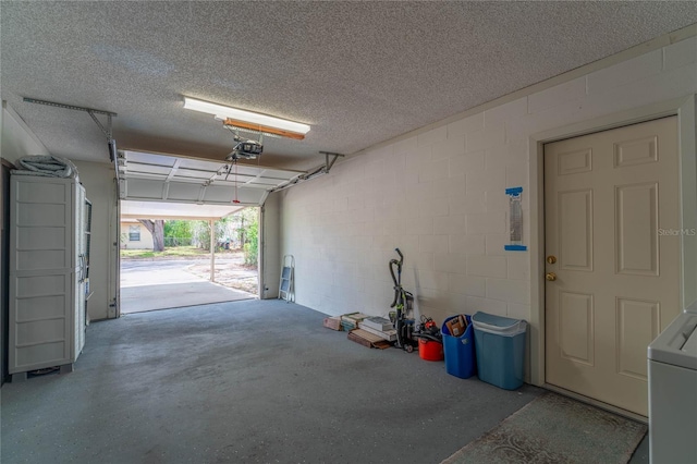 garage featuring washer / clothes dryer, concrete block wall, and a garage door opener
