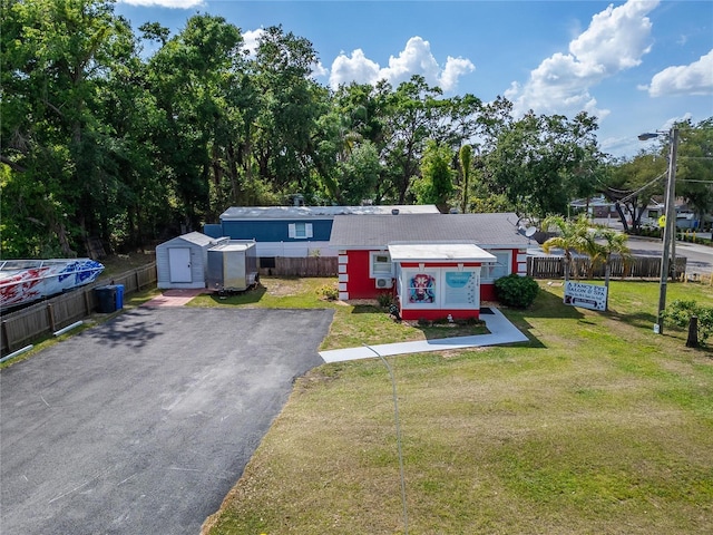 126 Ridgewood Ave, Brandon, FL 33510 - view of front facade with aphalt driveway, fence, a storage shed, an outbuilding, and a front yard