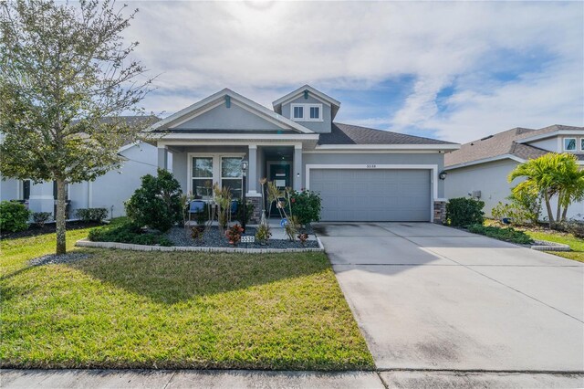 5538 Spanish Moss Cv, Bradenton, FL 34203 - view of front of house featuring an attached garage, a front yard, stone siding, driveway, and covered porch