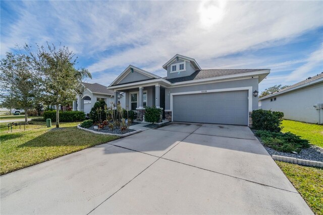 5538 Spanish Moss Cv, Bradenton, FL 34203 - view of front of house with stone siding, a front yard, an attached garage, driveway, and stucco siding
