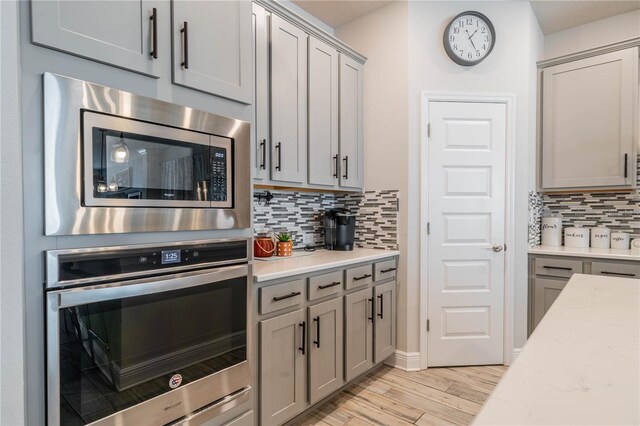 5538 Spanish Moss Cv, Bradenton, FL 34203 - kitchen featuring stainless steel appliances, gray cabinetry, decorative backsplash, and light wood-style floors