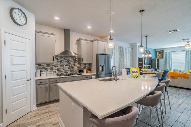 5538 Spanish Moss Cv, Bradenton, FL 34203 - kitchen with wall chimney exhaust hood, gray cabinets, stainless steel refrigerator with ice dispenser, a kitchen bar, and light wood-type flooring