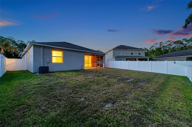 12831 White Bluff Rd, Hudson, FL 34669 - back of house at dusk featuring cooling unit, a sunroom, and stucco siding