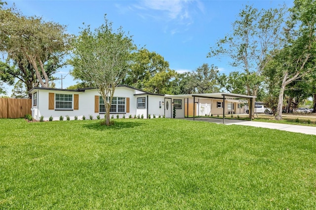 view of front of house featuring fence, a front lawn, stucco siding, a carport, and driveway