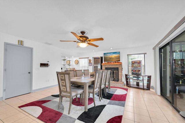 dining area featuring light tile patterned flooring, recessed lighting, ceiling fan, a brick fireplace, and baseboards