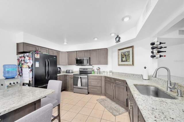 kitchen with light stone countertops, recessed lighting, light tile patterned floors, a sink, and stainless steel appliances