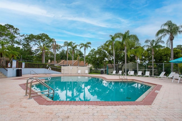 community pool with fence and a patio area