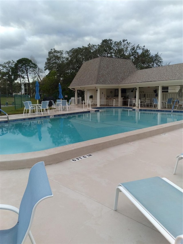community pool with fence and a patio