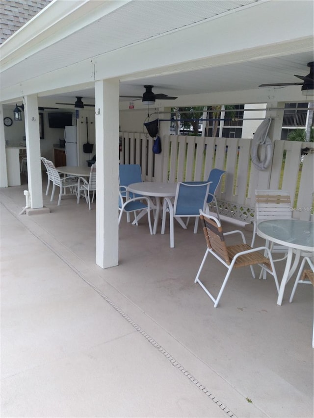 view of patio with fence, a ceiling fan, and outdoor dining space