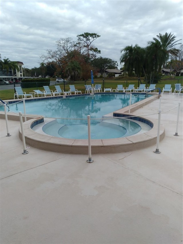 community pool featuring a lawn and a patio area