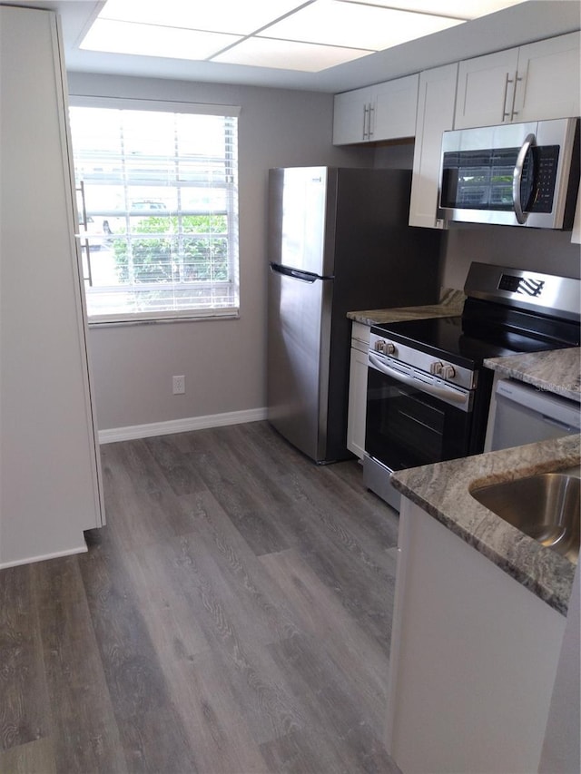 kitchen featuring light stone countertops, baseboards, white cabinets, dark wood-style floors, and stainless steel appliances
