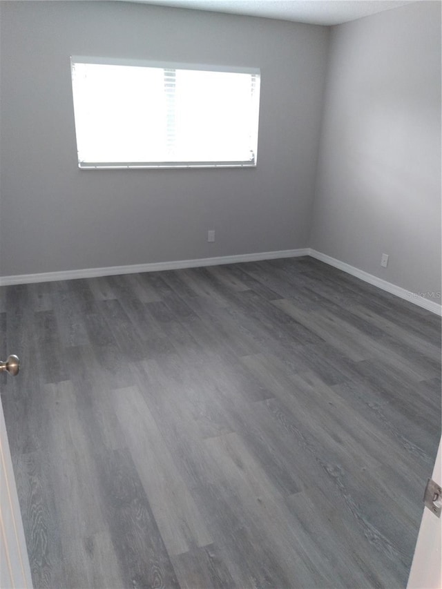 unfurnished room featuring baseboards and dark wood-style floors
