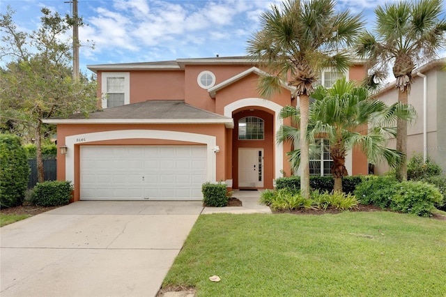mediterranean / spanish-style home with a garage, stucco siding, driveway, and a front yard