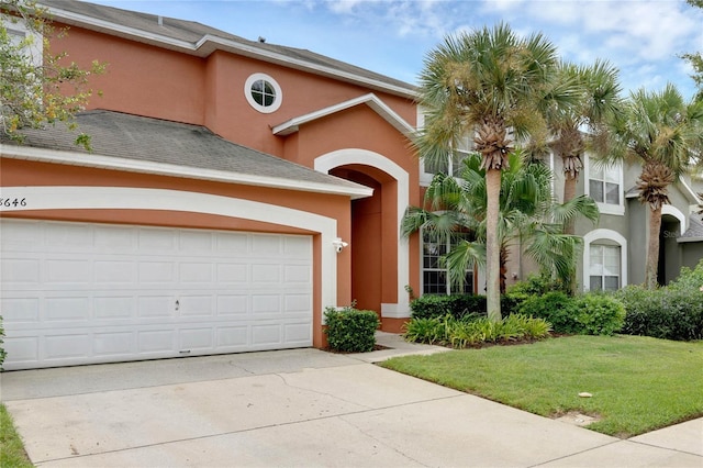 mediterranean / spanish-style home with concrete driveway, a front yard, and stucco siding