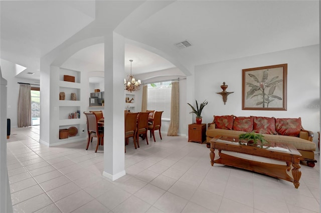 living room featuring visible vents, built in features, arched walkways, light tile patterned floors, and an inviting chandelier