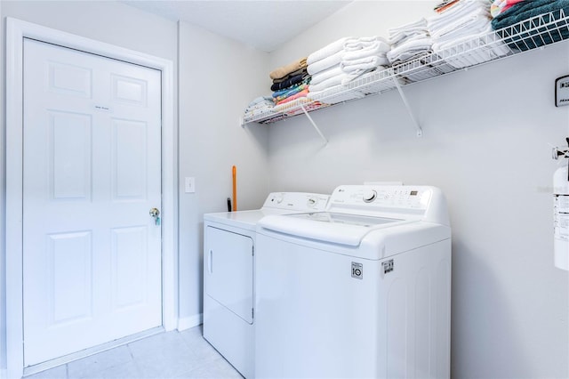 laundry area with laundry area, washing machine and dryer, and light tile patterned flooring
