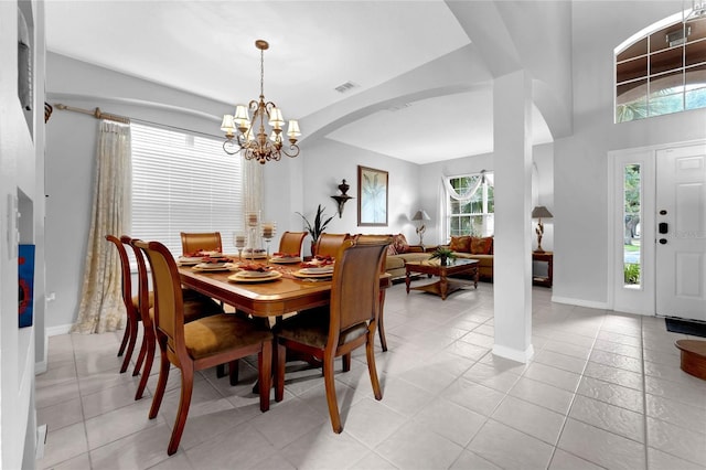 dining area featuring an inviting chandelier, visible vents, baseboards, arched walkways, and light tile patterned floors