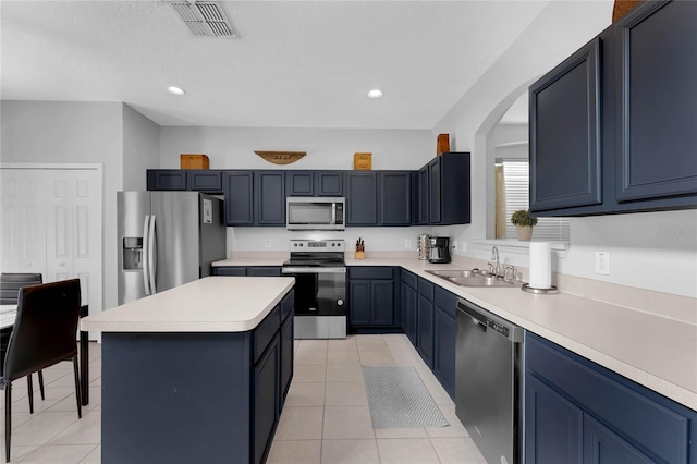 kitchen with light tile patterned flooring, a sink, light countertops, a center island, and stainless steel appliances