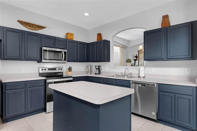 kitchen featuring arched walkways, a sink, light tile patterned floors, light countertops, and stainless steel appliances
