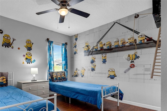 bedroom featuring baseboards, a ceiling fan, a textured ceiling, and wood finished floors