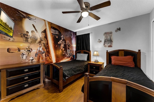 bedroom with a textured ceiling, ceiling fan, and wood finished floors