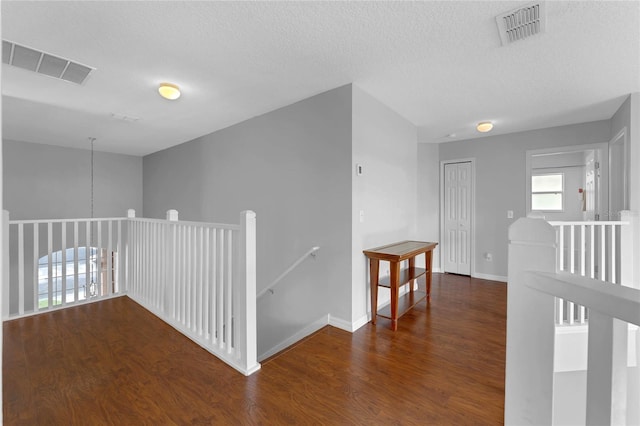hall with an upstairs landing, wood finished floors, and visible vents