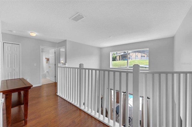 corridor featuring baseboards, visible vents, and wood finished floors